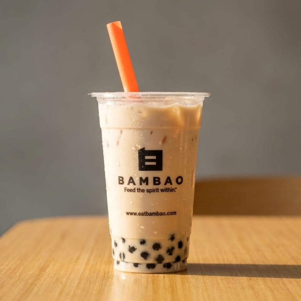 Bambao bubble tea with an orange straw on a wooden table against a gray background.